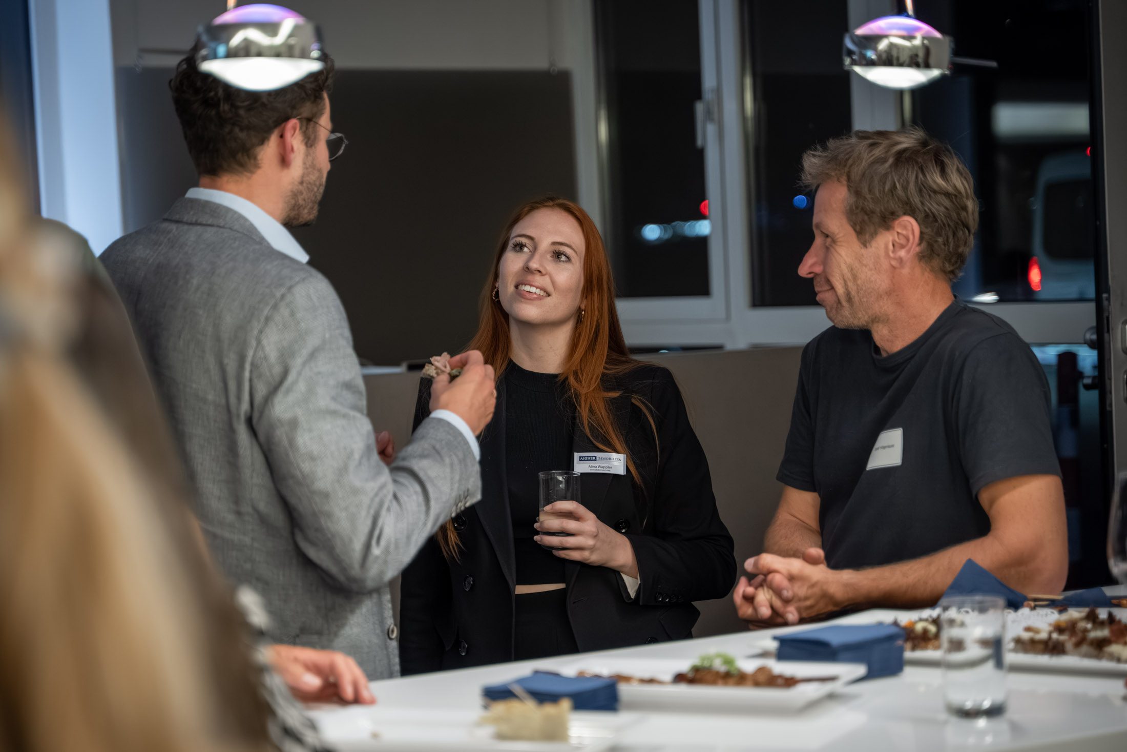Drei Personen im Gespräch über Immobilienthemen bei Event mit Catering