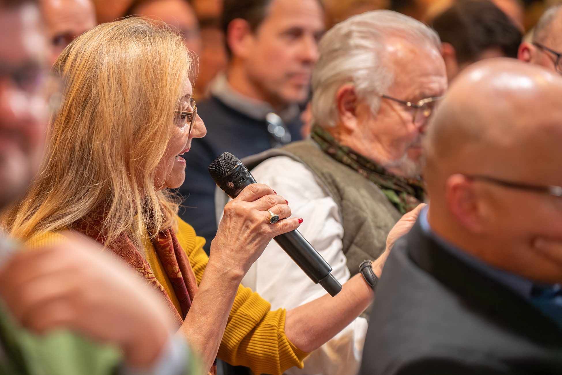 Publikumsfrage beim Münchner Immobilien Fokus 2025 Teilnehmerin stellt engagiert eine Frage an das Podium beim Münchner Immobilien Fokus 2025