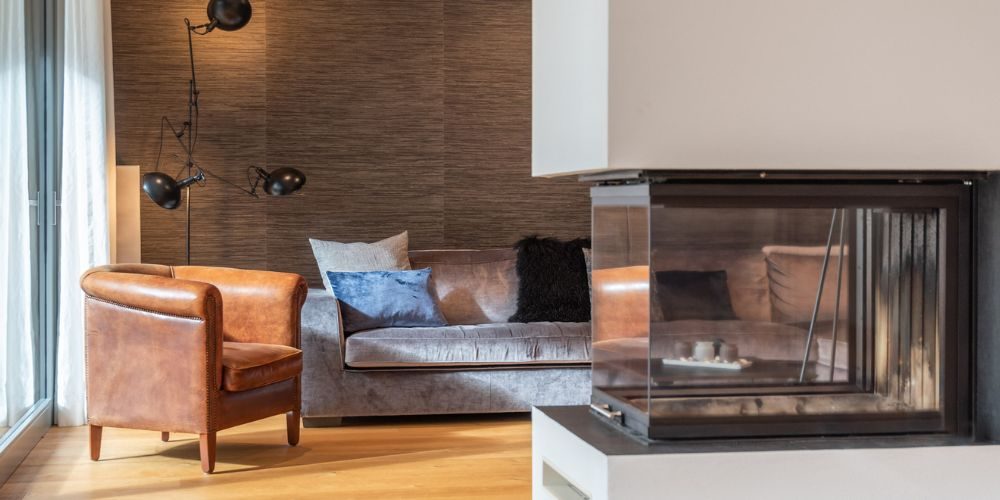 Wohnzimmer einer exklusiven Immobilie (33461) Gemütliches Wohnzimmer mit Ledersessel, Designerlampe und Kamin in einem modernen Haus in München