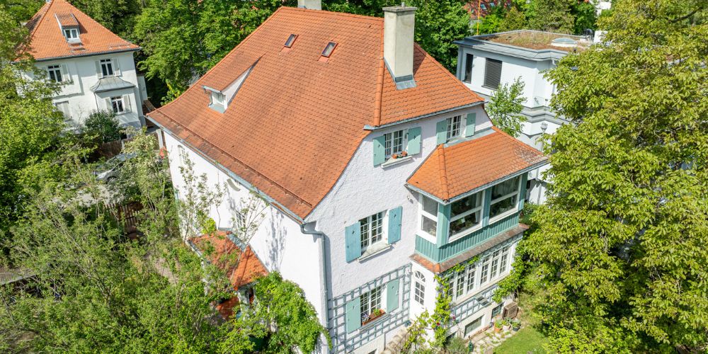 Charmante Stadtvilla in Bestlage von München (41979) Luftaufnahme einer stilvollen Stadtvilla mit rotem Satteldach, Fensterläden und Wintergarten in ruhiger, grüner Wohnlage in München
