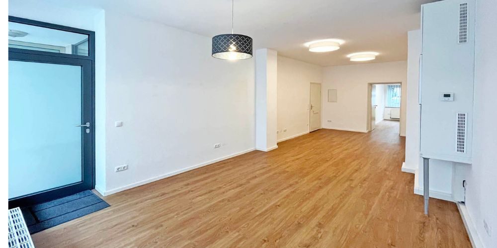 Helle, frisch renovierte Büroräume in München mit Glas-Eingangstür, LED-Deckenleuchten, weiß gestrichenen Wänden
