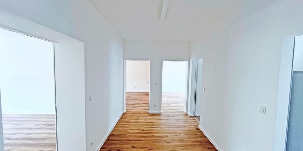 Heller Flur einer modernen Wohnung mit weiß gestrichenen Wänden und hochwertigem Echtholzparkett in München