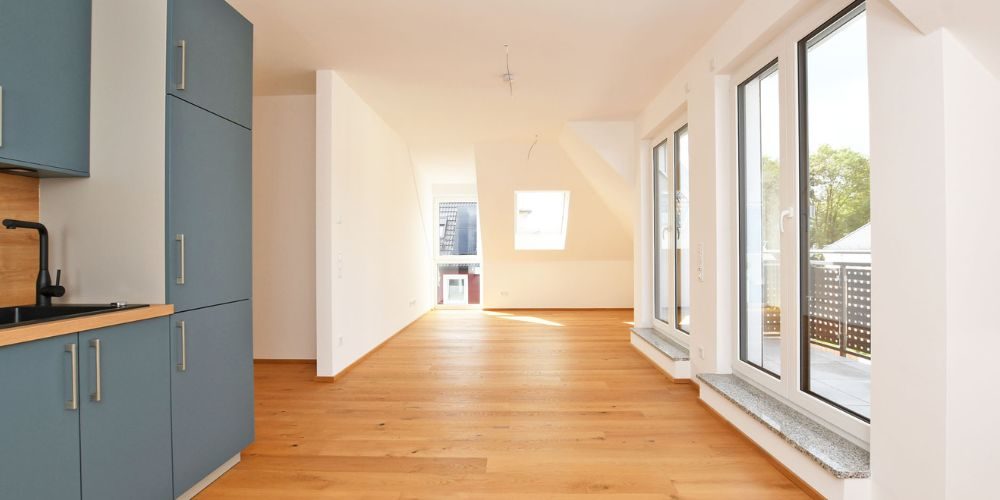 Lichtdurchflutete Neubauwohnung in München mit moderner blauer Einbauküche, bodentiefen Fenstern und hochwertigem Eichenparkett