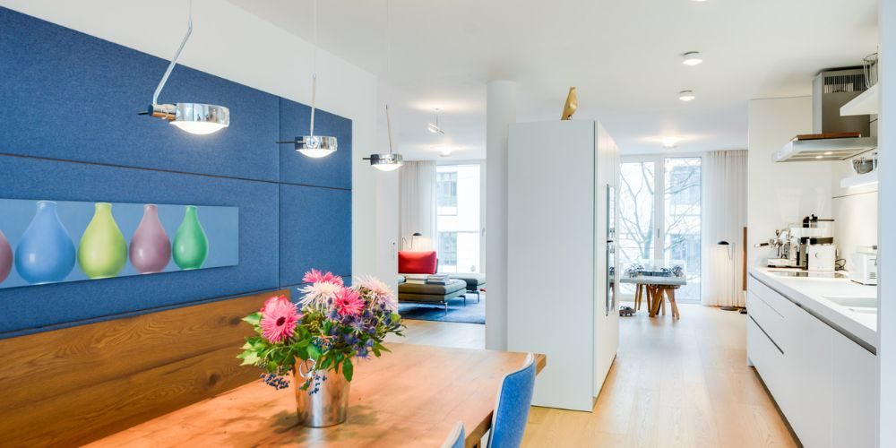 Helles Wohn- und Esszimmer in München mit moderner weißer Einbauküche, Holzboden, stilvoller Beleuchtung und Blumenarrangement auf dem Esstisch