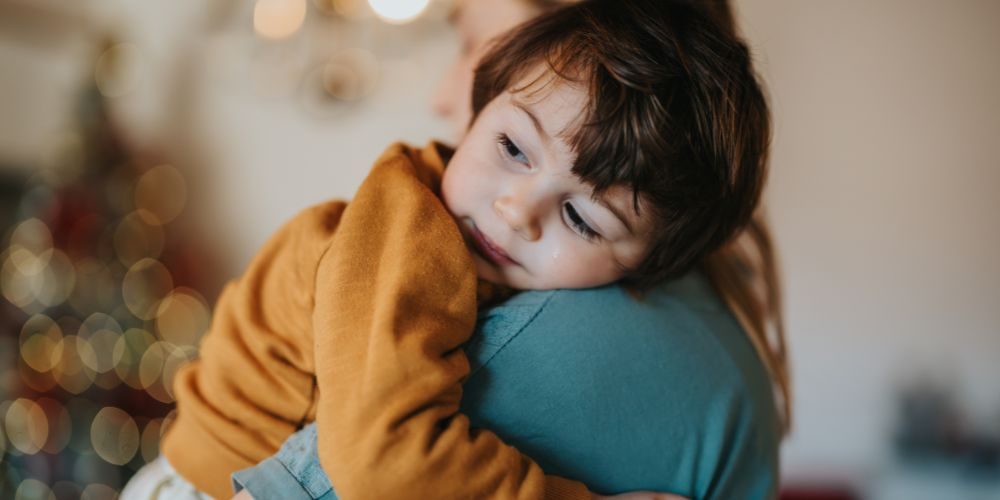 Mutter hält ihr Kind in den Armen, das Kind wirkt entspannt und sicher