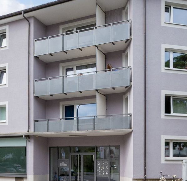 Fassade eines sanierten Mehrfamilienhauses mit Balkonen und Gewerbeeinheiten im Erdgeschoss in München