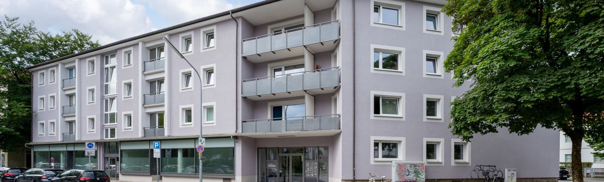Fassade eines sanierten Mehrfamilienhauses mit Balkonen und Gewerbeeinheiten im Erdgeschoss in München