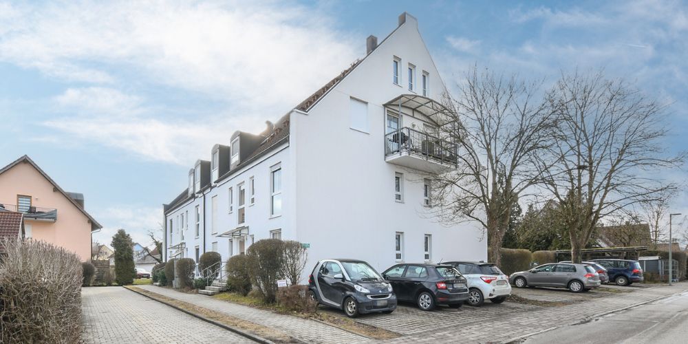 Helles Mehrfamilienhaus mit Balkonen und Parkplätzen in ruhiger Wohnstraße in München, gepflegte Wohnanlage mit moderner Architektur
