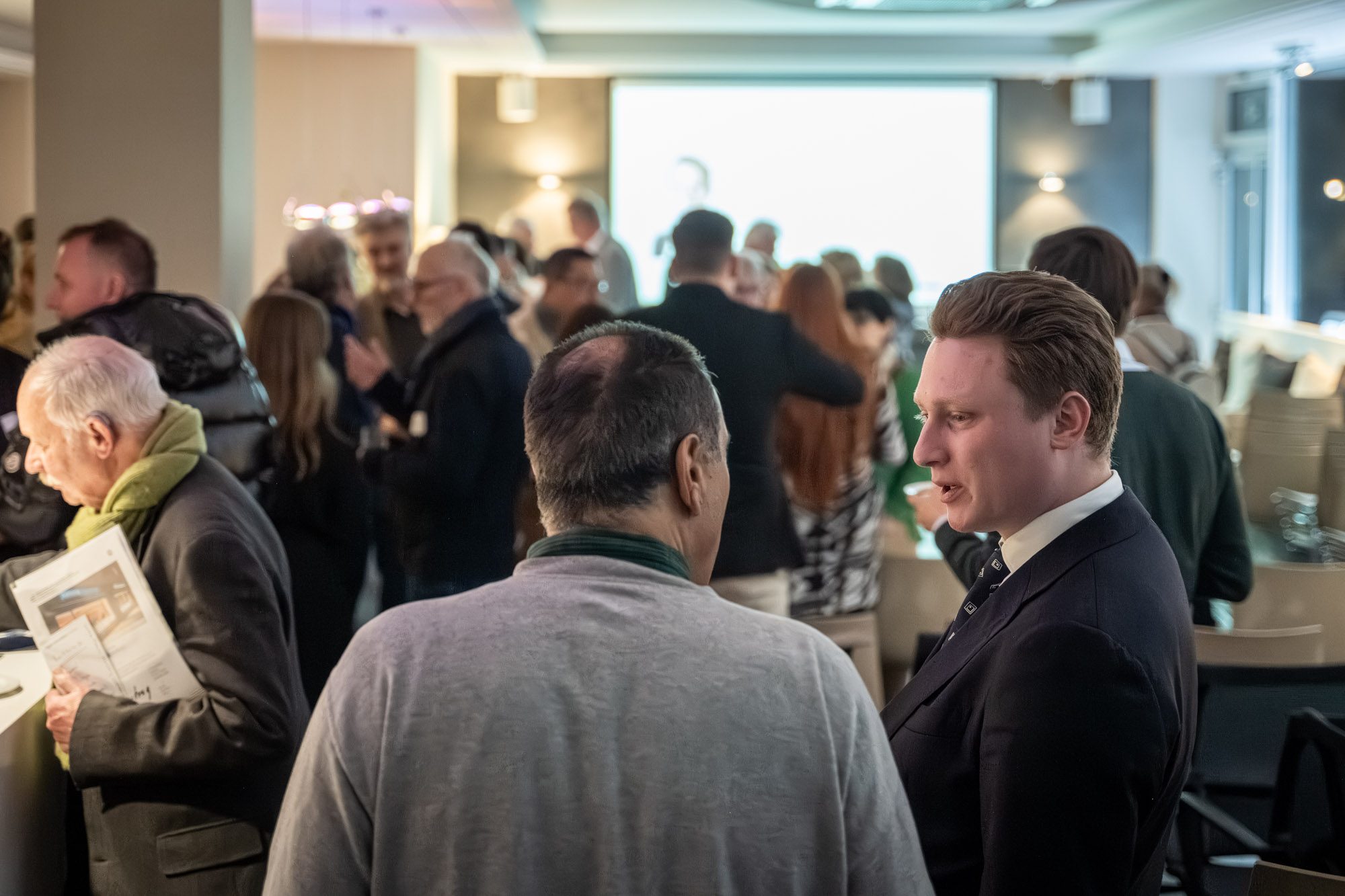Besucher im Gespräch bei exklusiver Immobilienveranstaltung in München