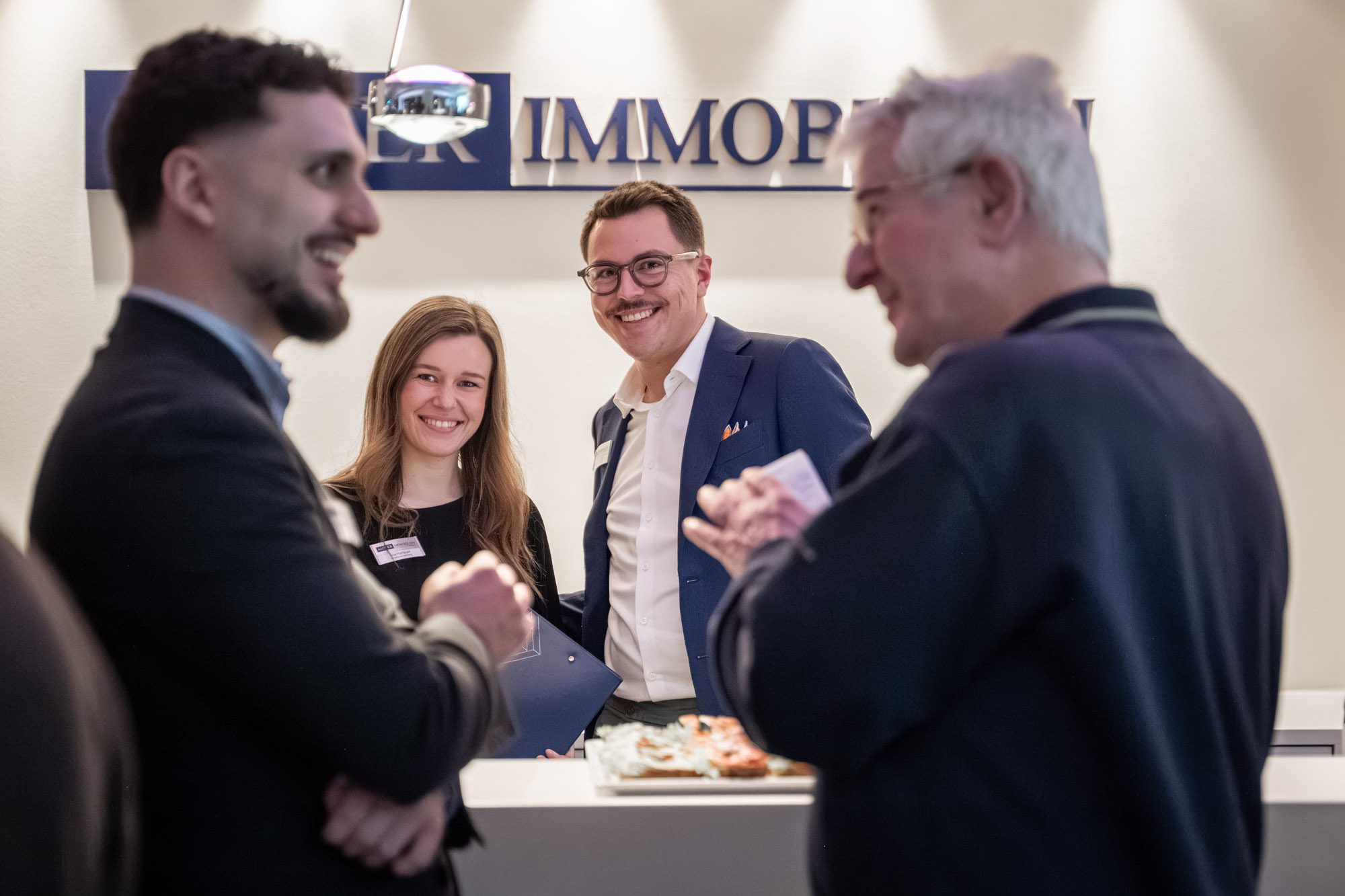 Maklerteam von Aigner Immobilien im Gespräch mit Kunden bei Networking-Veranstaltung in München