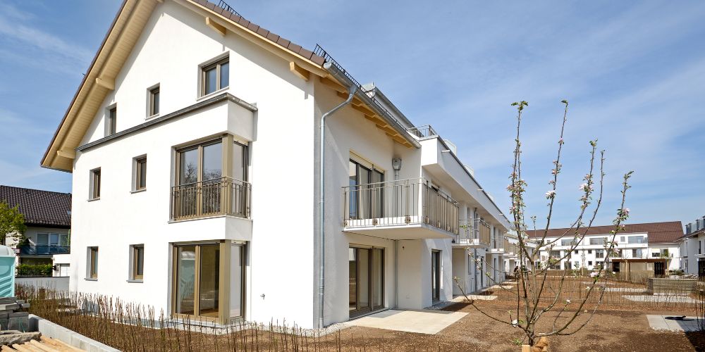 Moderne weiße Mehrfamilienhaus-Neubauten mit Balkonen und Erdgeschoss-Terrassen in einer neu angelegten Wohnanlage