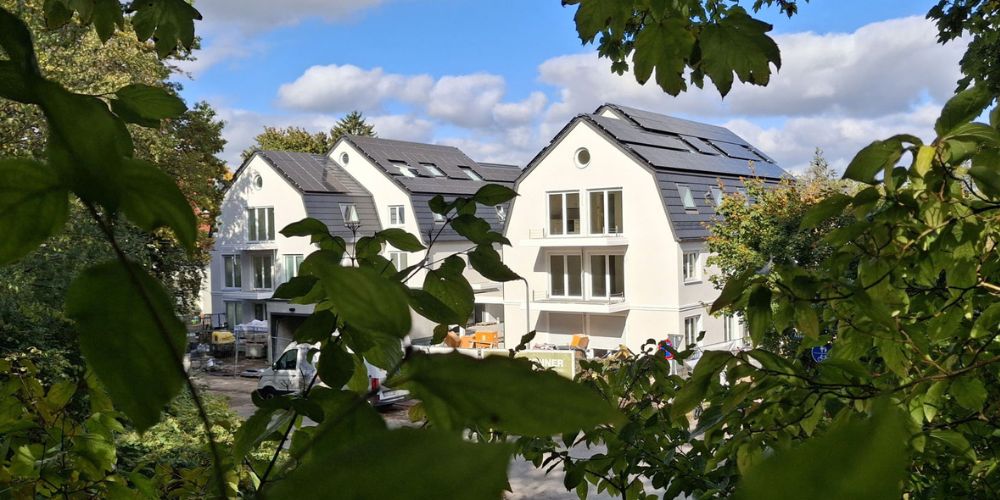 Neubauprojekt mit modernen Häusern, Solaranlagen auf dem Dach, in grüner Umgebung und im Bauzustand