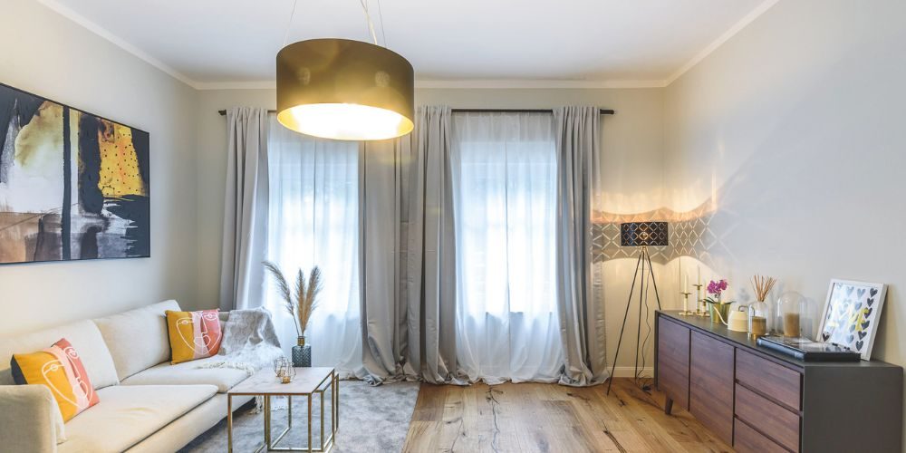 Modernes Wohnzimmer mit Sofa, stilvollem Couchtisch, eleganter Beleuchtung und dekorativen Akzenten in warmen Farbtönen