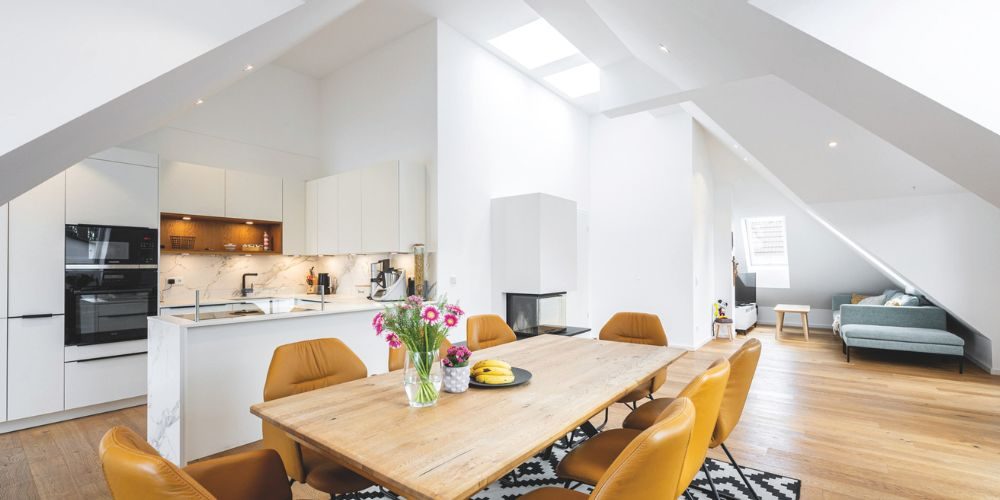 Helles Loft mit offener Küche, Esstisch, modernen Stühlen und gemütlicher Sitzecke unter Dachschrägen