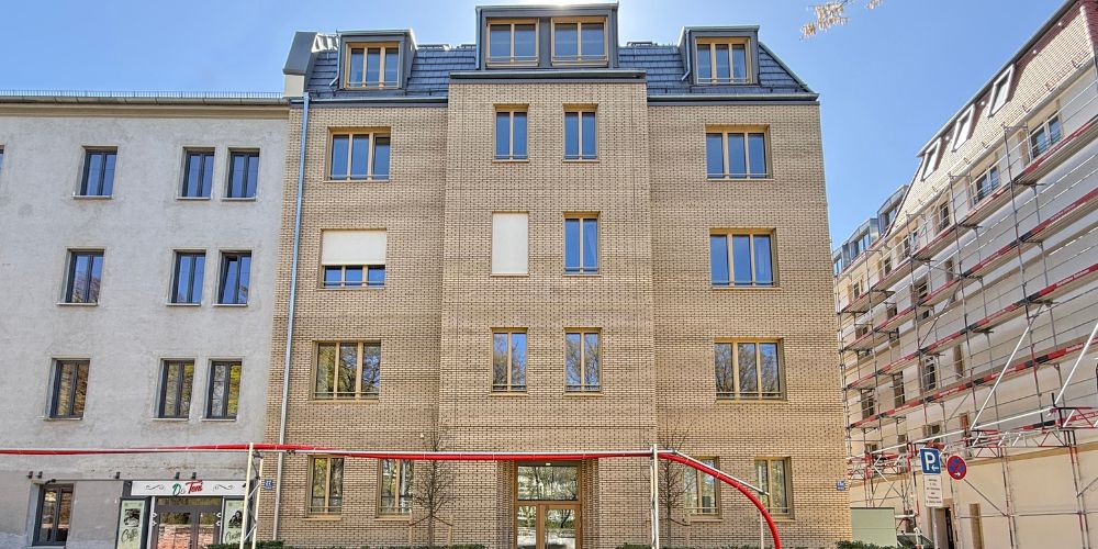 Modernes Neubaugebäude mit Ziegelsteinfassade, klaren Linien und großen Fenstern in städtischer Umgebung