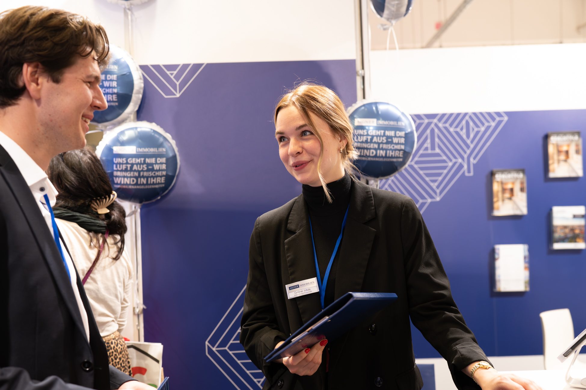 Immobilienmaklerin am Stand von Aigner Immobilien