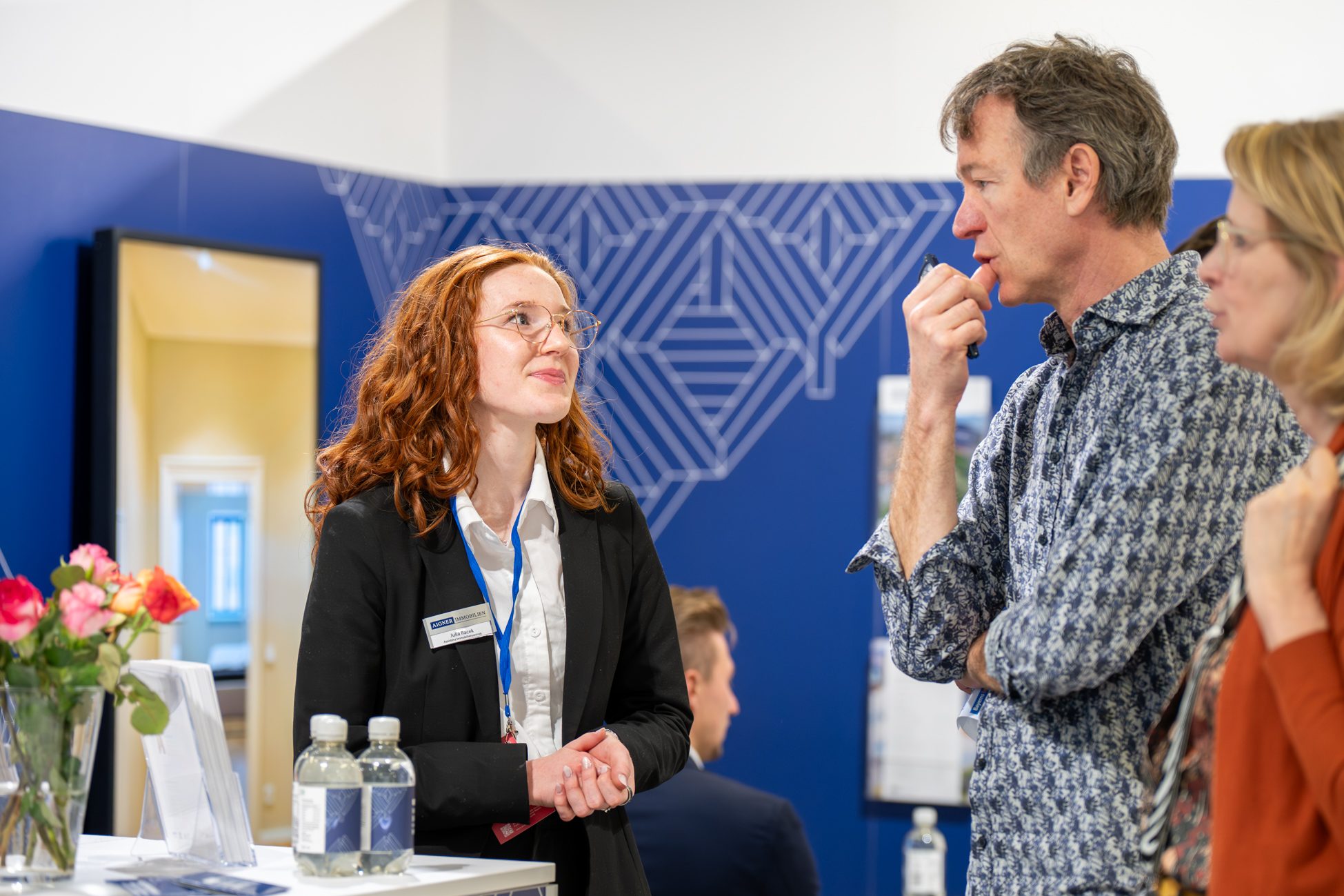 Individuelle Immobilienberatung auf einer Messe in München: Eine Maklerin im Gespräch mit Interessenten zu Kauf, Verkauf und Bewertung von Immobilien. Persönlicher Austausch und professionelle Expertise im Fokus.