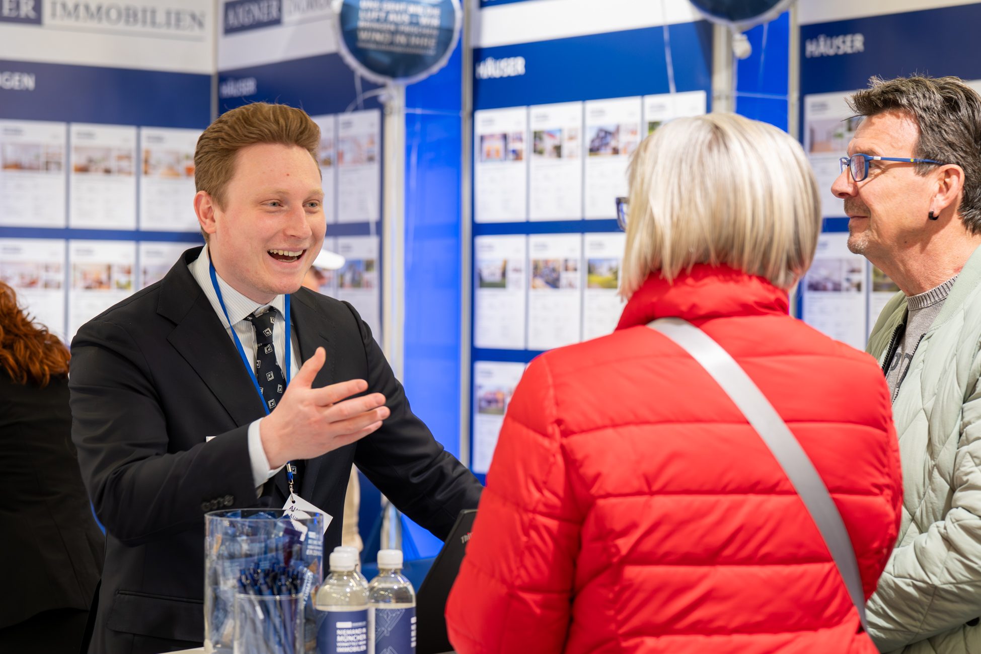 Immobilienmakler im Gespräch mit Kunden am Messestand
