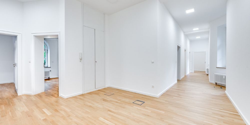 Weiß gestrichener Flur mit hohen Decken, mehreren Türen und hellem Parkettboden in einem Altbau-Büro