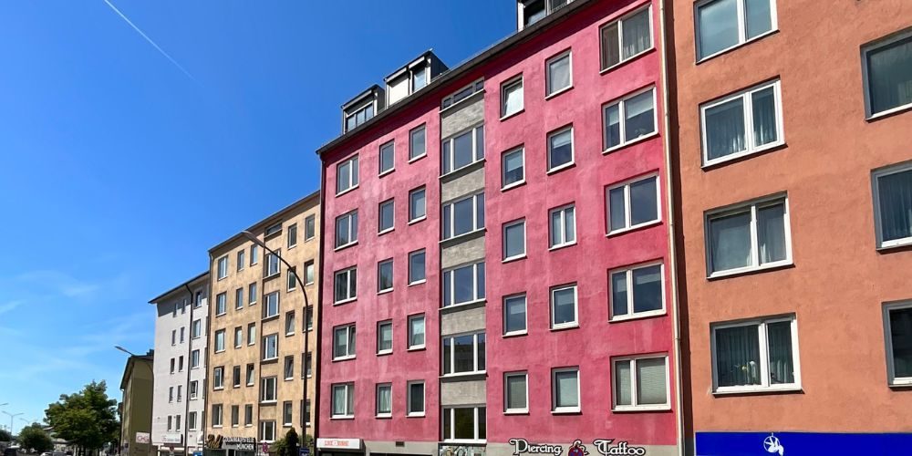 Modernisiertes Mehrfamilienhaus in München mit farbiger Fassadengestaltung, mehreren Wohneinheiten und Gewerbeflächen im Erdgeschoss in urbaner Wohnlage