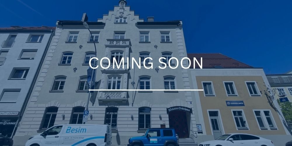 Historisches Wohn- und Geschäftshaus mit heller Fassade und dekorativen Stilelementen an einer innerstädtischen Straße in München