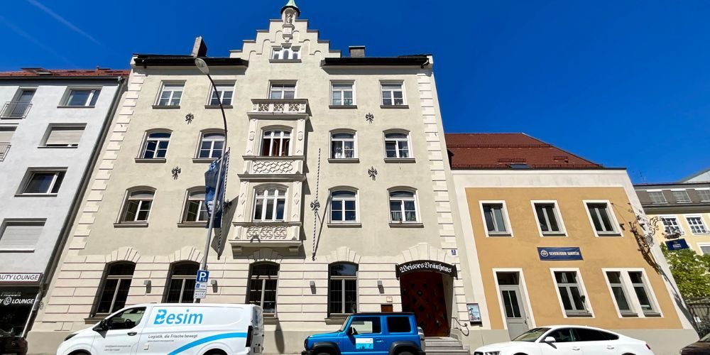 Historisches Wohn- und Geschäftshaus mit heller Fassade und dekorativen Stilelementen an einer innerstädtischen Straße in München