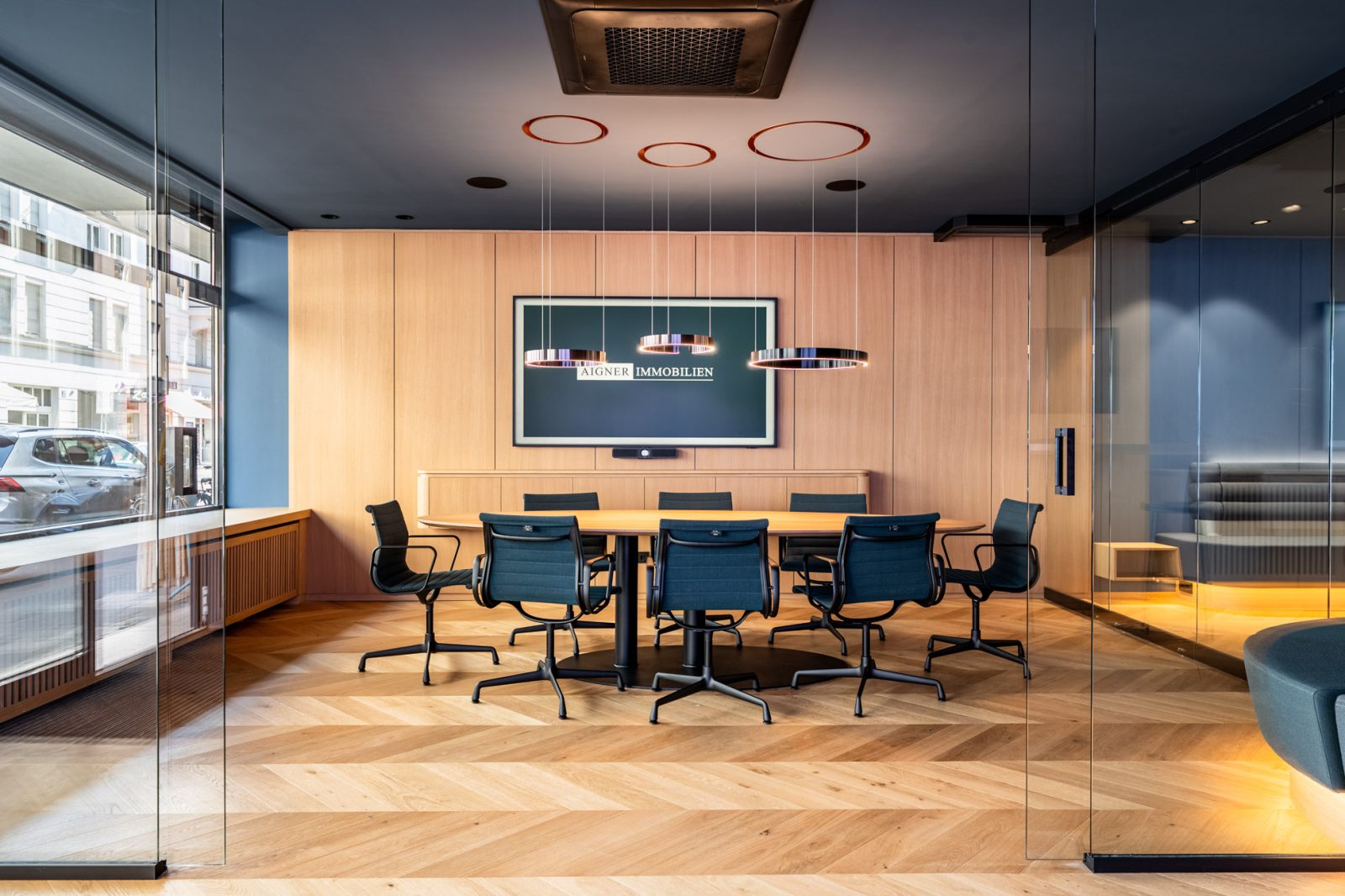 Heller Konferenzraum mit großem Besprechungstisch, Designleuchten und Glaswänden im Immobilienbüro in Schwabing von Aigner Immobilien