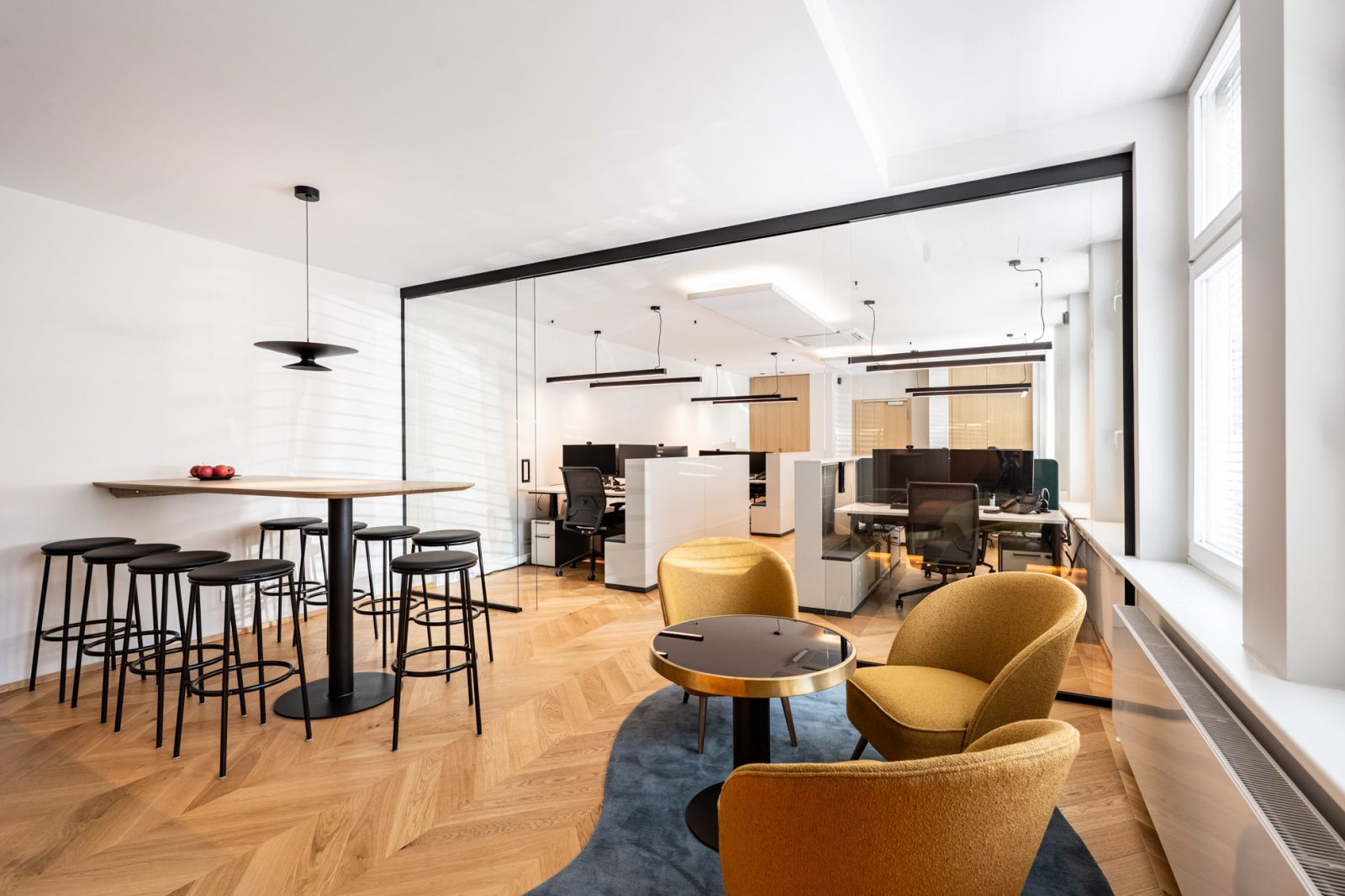 Moderne Bürofläche mit Loungebereich, Stehtisch, Glasabtrennung und Open-Space-Arbeitsplätzen in einem Immobilienbüro in München