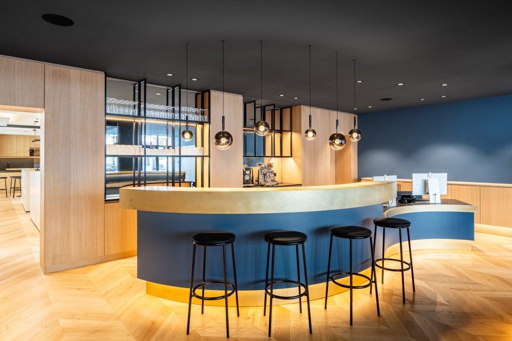 Moderne Empfangstheke mit Barhockern, Designbeleuchtung und hochwertiger Ausstattung im Maklerbüro in München
