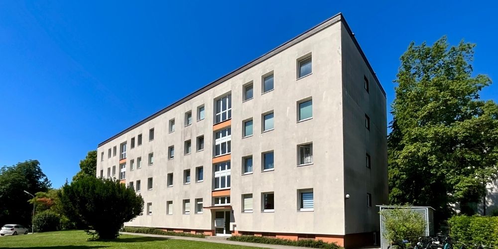 Mehrfamilienhaus in München (44084) Außenansicht eines mehrgeschossigen Mehrfamilienhauses in München mit heller Fassade und großen Bäumen