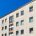 Außenansicht eines mehrgeschossigen Mehrfamilienhauses in München mit heller Fassade und großen Bäumen
