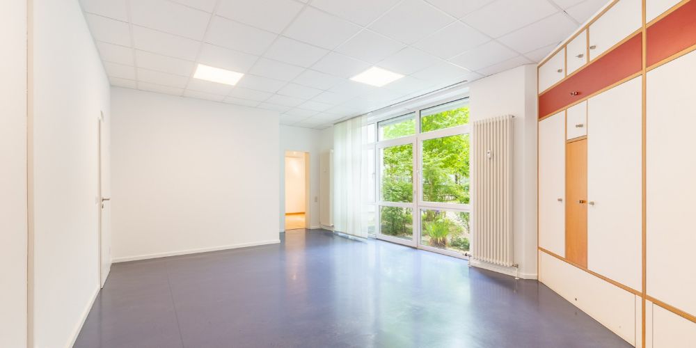Ansicht eines Büros mit großer Fensterfront und Blick auf einen grünen Baum