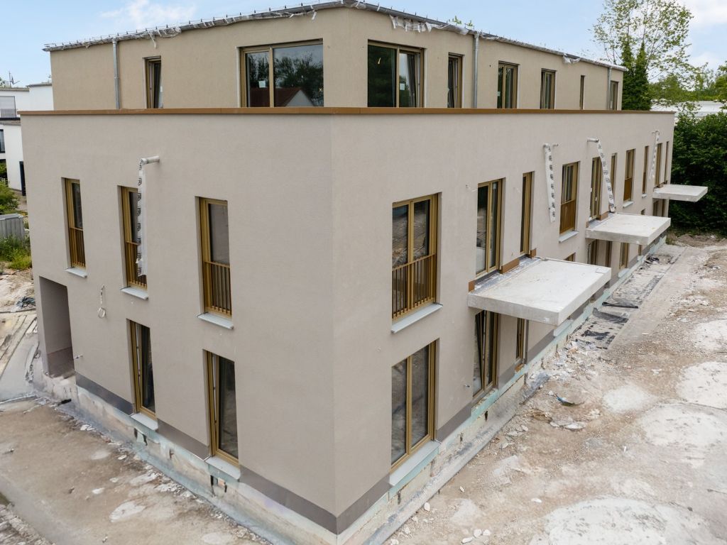 Neubau Mehrfamilienhaus mit heller Fassade und modernen Balkonen in München vor der Fertigstellung