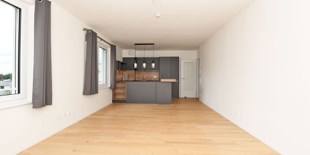 Heller Wohn- und Essbereich mit moderner Einbauküche, Holzboden und großen Fenstern in einer Münchner Immobilie