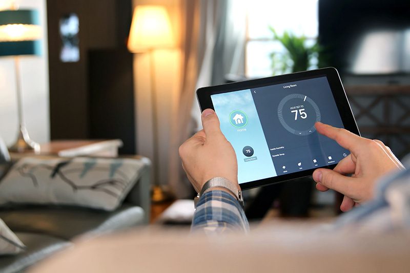 Eine Person bedient ein Tablet mit Smart-Home-App zur Temperatursteuerung
