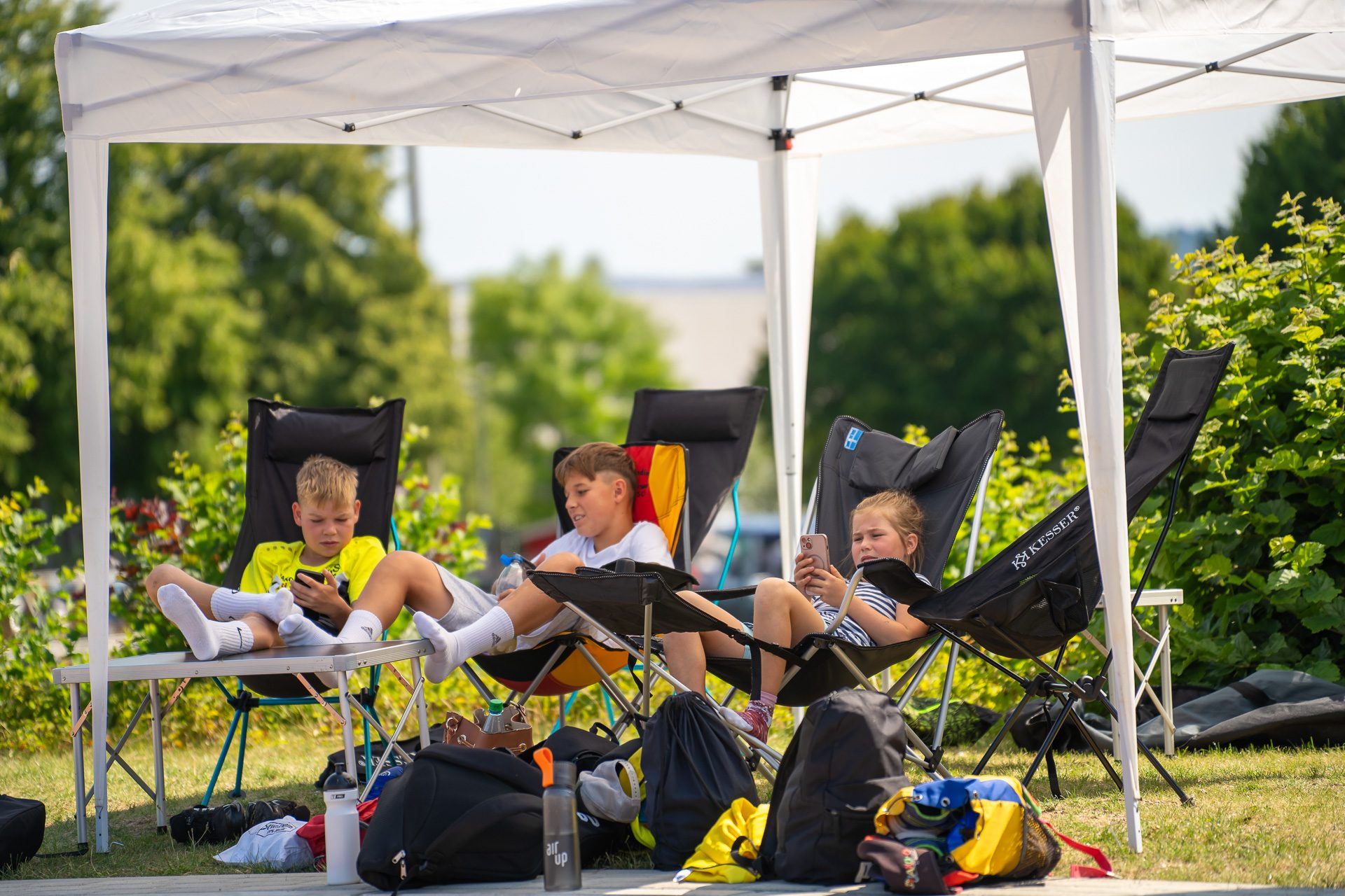A7302517 3 Kinder sitzen unter Pavillion im Schatten