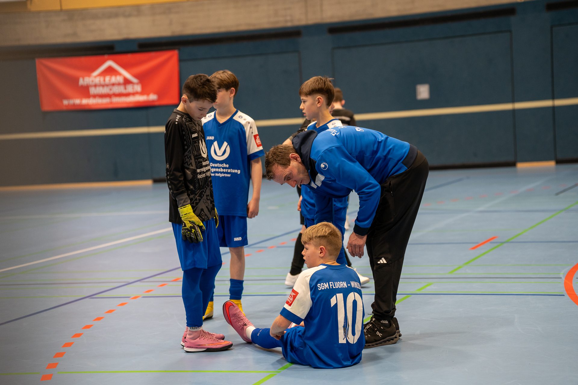 B7302252 Spieler sitzt auf dem Boden nach einem Foul und wird vom Trainer getröstet