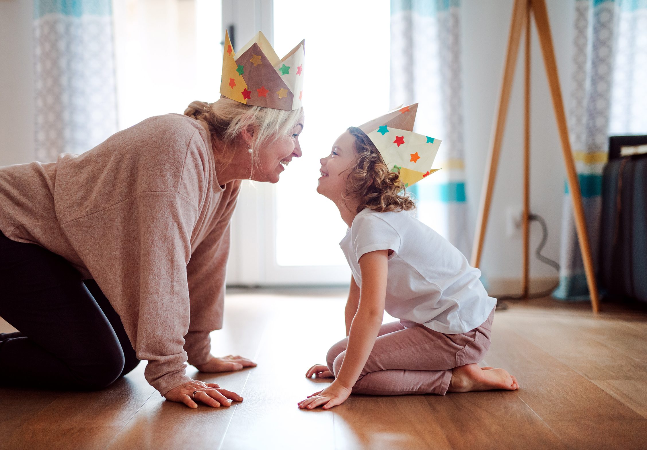 A portrait of small girl with grandmother having fun at home.
