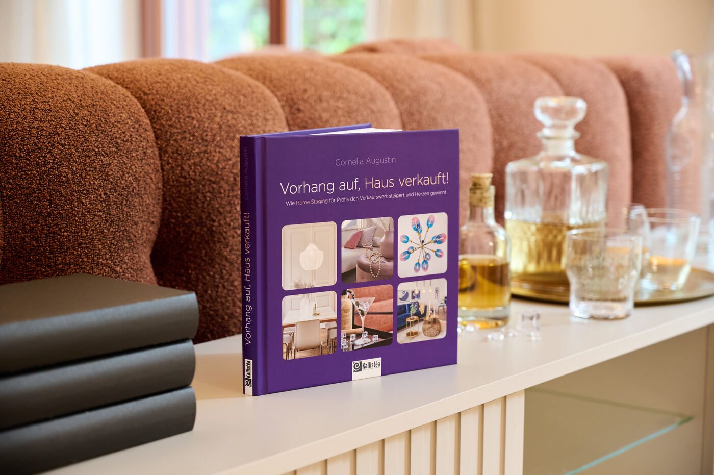 Buch „Vorhang auf, Haus verkauft!“ von Cornelia Augustin auf einem Sideboard