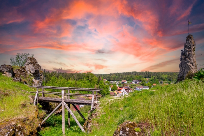 Idyllischer Sonnenuntergang in Hollfeld mit kleiner Holzbrücke und markanter Felsformation
