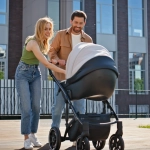 Junge Familie mit Kinderwagen in moderner Wohnanlage